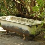 an old bath tub sitting in the middle of a garden